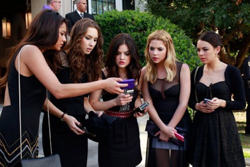 The Pretty Little Liars girls crowd around a mobile phone with surprised faces
