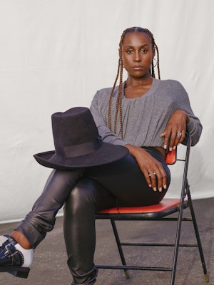 Issa Rae sitting in an Alexander Wang grey top and black Gucci hat, Ben Oni earrings and a Third Cro...