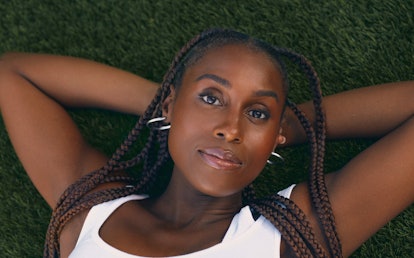 Issa Rae lying on the grass in a white Kendra Duplantier top and Ben Oni hoop earrings