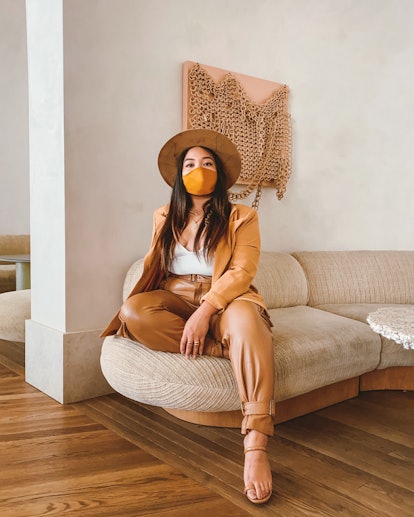 A woman sitting on a couch while wearing a face mask