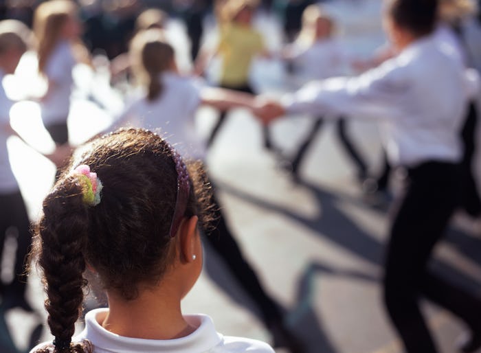 child on school playground watching classmates play from a distance