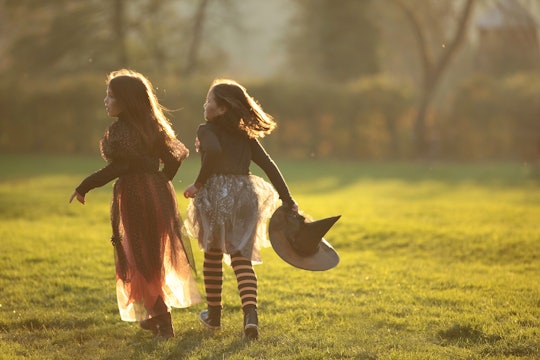 Two tweens in halloween costumes running through a lawn