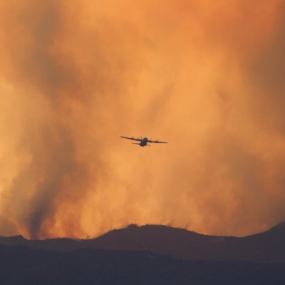 Low Angle View Of Silhouette Airplane Flying Against Sky During Wildfire