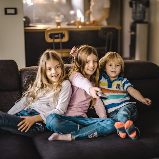 children sitting on the couch watching television