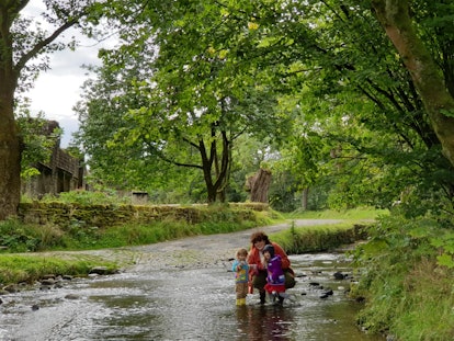 Mother and two kids standing in a shallow river