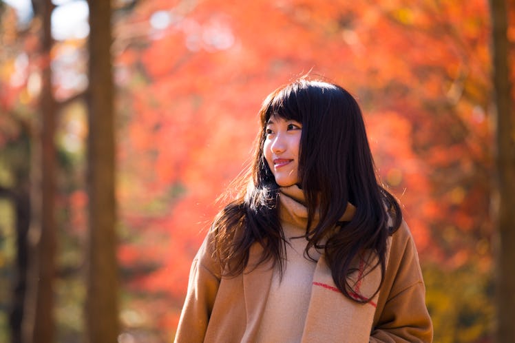 Young woman walking in autumn/fall foliage, which is her zodiac sign's favorite thing about fall.
