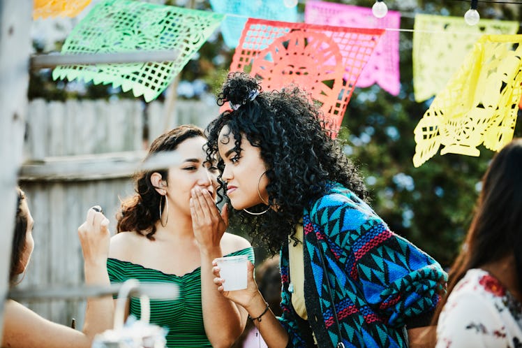 Woman whispering to friend during backyard party