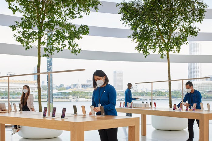 Four Apple employees in face masks adjust iPhones at the new Marina Bay Sands store.