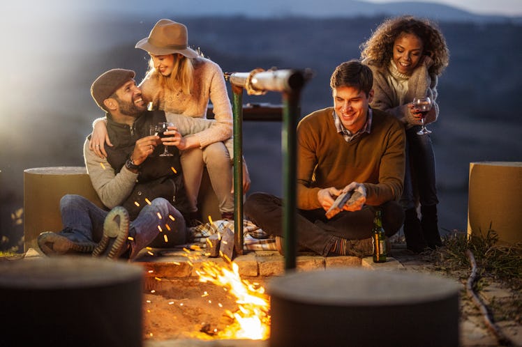 Friends around a bonfire, their zodiac sign's favorite thing about fall.