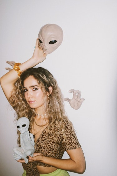 Haley Lu Richardson: with alien head and a small alien in her hands.