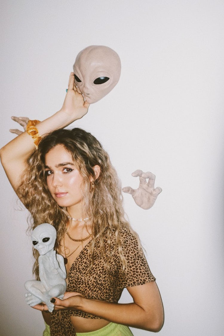 Haley Lu Richardson: with alien head and a small alien in her hands.