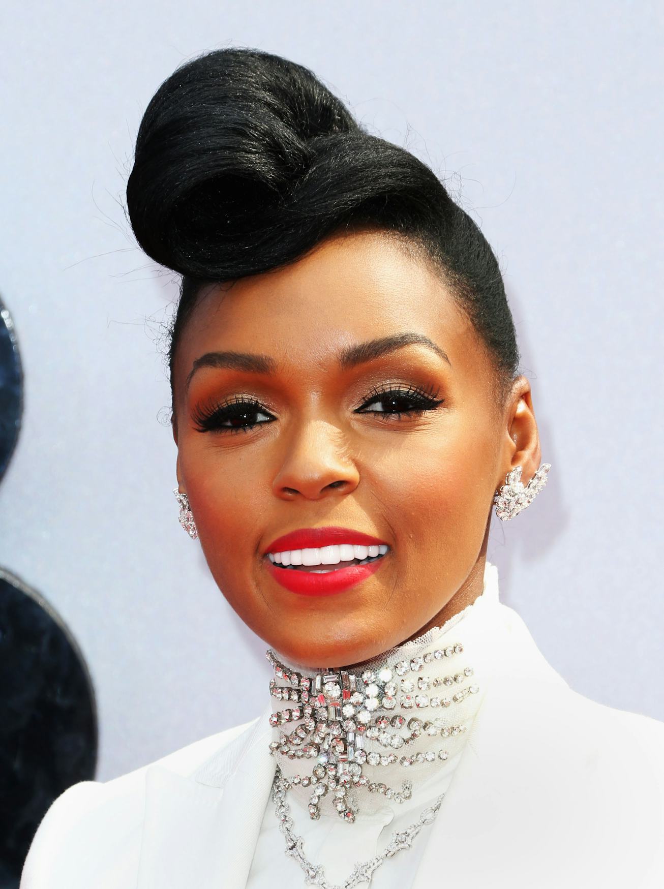 Janelle Monáe wearing red lipstick and a bouffant updo.