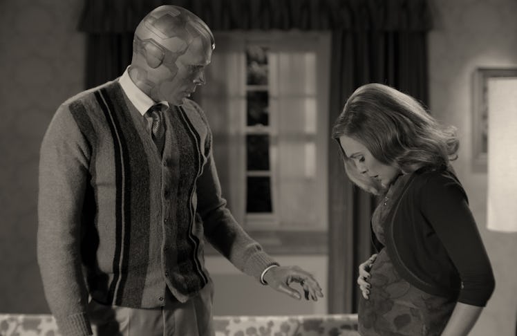 Elizabeth Olsen and Paul Bettany in WandaVision, with Elizabeth's character looking down at her bell...