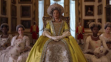 Queen Charlotte from 'Bridgerton' wears a yellow ballgown while sitting in front of her ladies.