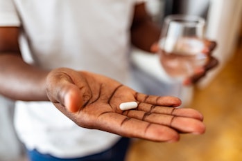 Man's hand holding a pill