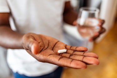 Man's hand holding a pill