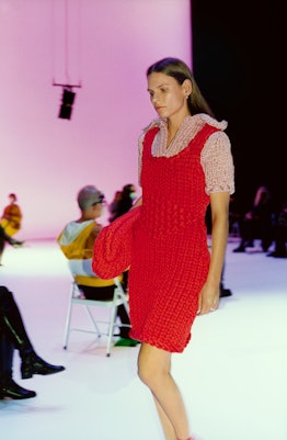 A model walking the runway in a red crochet dress and a matching clutch by Bottega Veneta