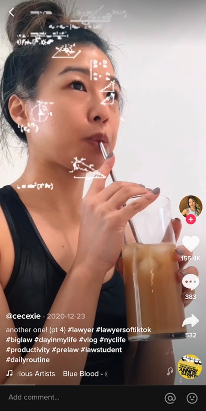 A young woman sips iced coffee and works while filming a daily vlog for TikTok.