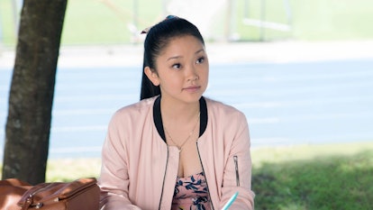 Lara Jean from 'To All the Boys I've Loved Before' sits at a picnic table while wearing a pink bombe...