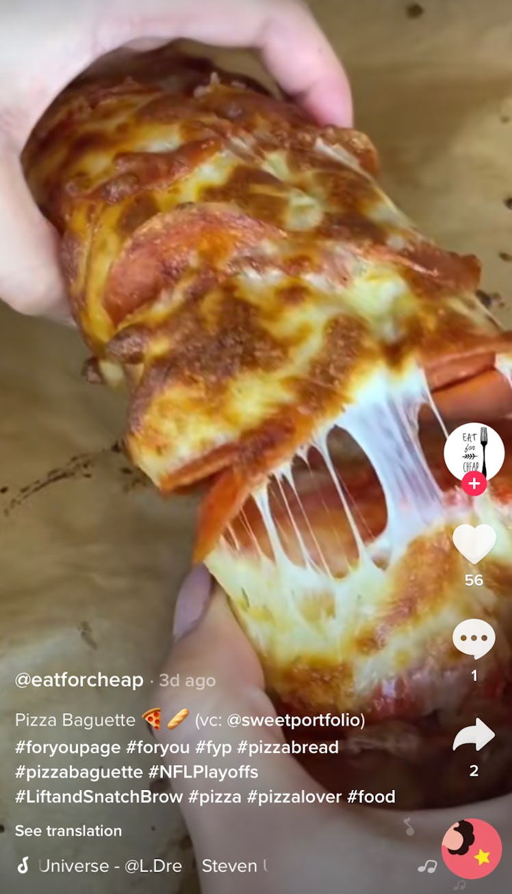 A woman breaks apart a pizza baguette in her kitchen. 