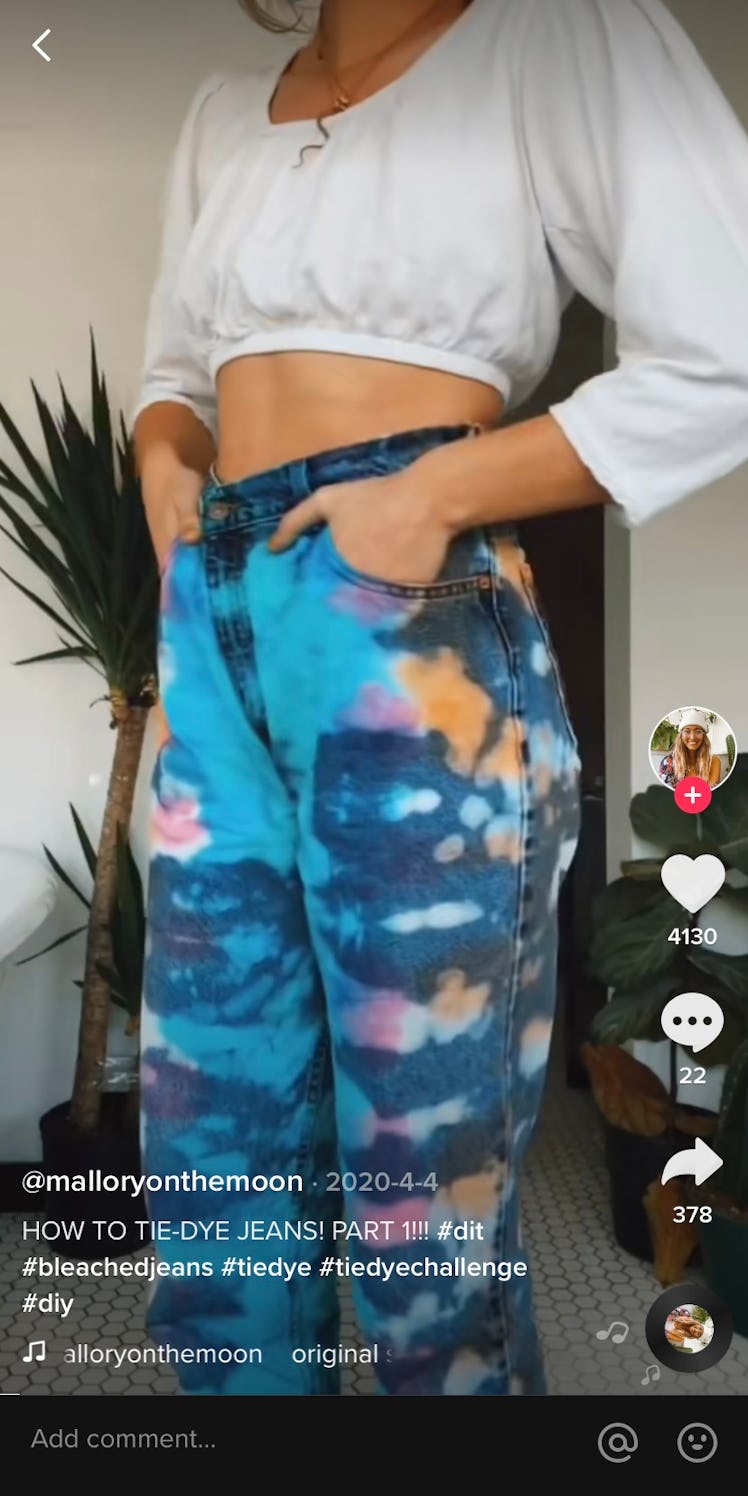 A TikTok poses in colorful, bleach tie-dyed jeans in a video.