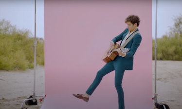 Joshua Bassett plays guitar in front of a pink backdrop in the desert in the music video for "Lie Li...