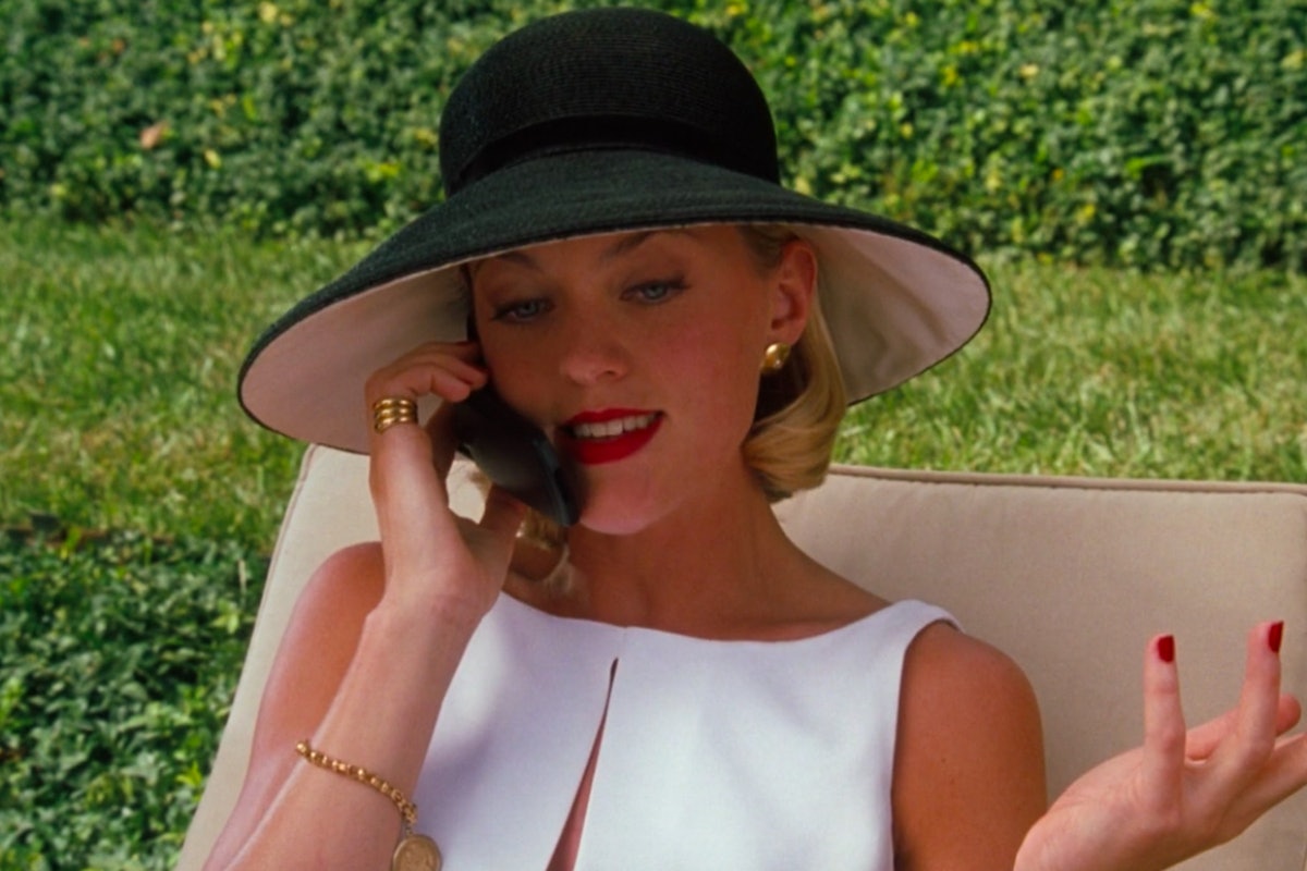 Meredith Blake talking on her phone and wearing a white shirt and black hat