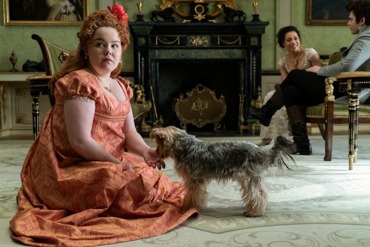 Penelop Featherington from 'Bridgerton' sits on the floor with a dog, while Marina and Colin talk.