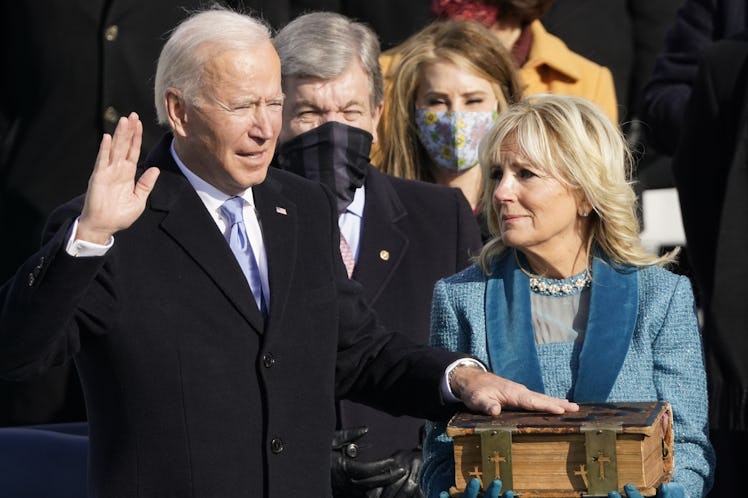 Jill Biden holding up a large Bible while President Joe Biden recites the Presidential Oath.
