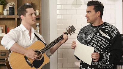 Patrick holds a guitar, while talking to David in Rose Apothecary in 'Schitt's Creek.'