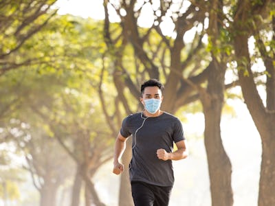 young man in face mask and running in the park