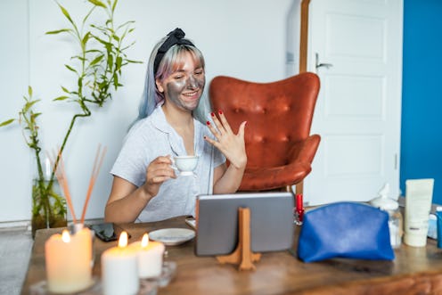 A woman sitting at home with a facemask looking at her iPad during Galentine's celebrations