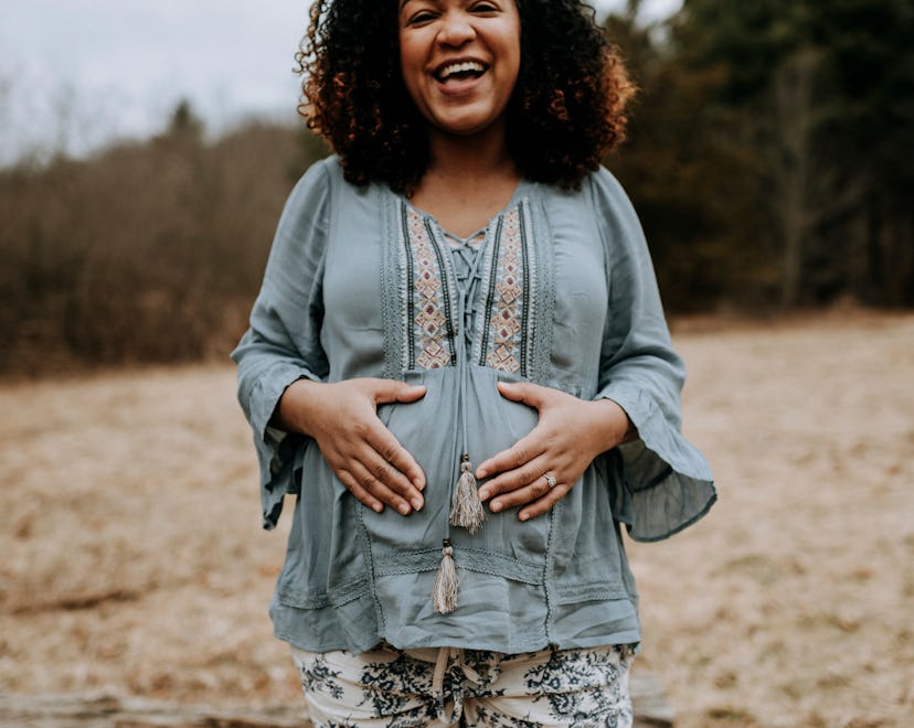 Happy pregnant woman smiling and holding her belly