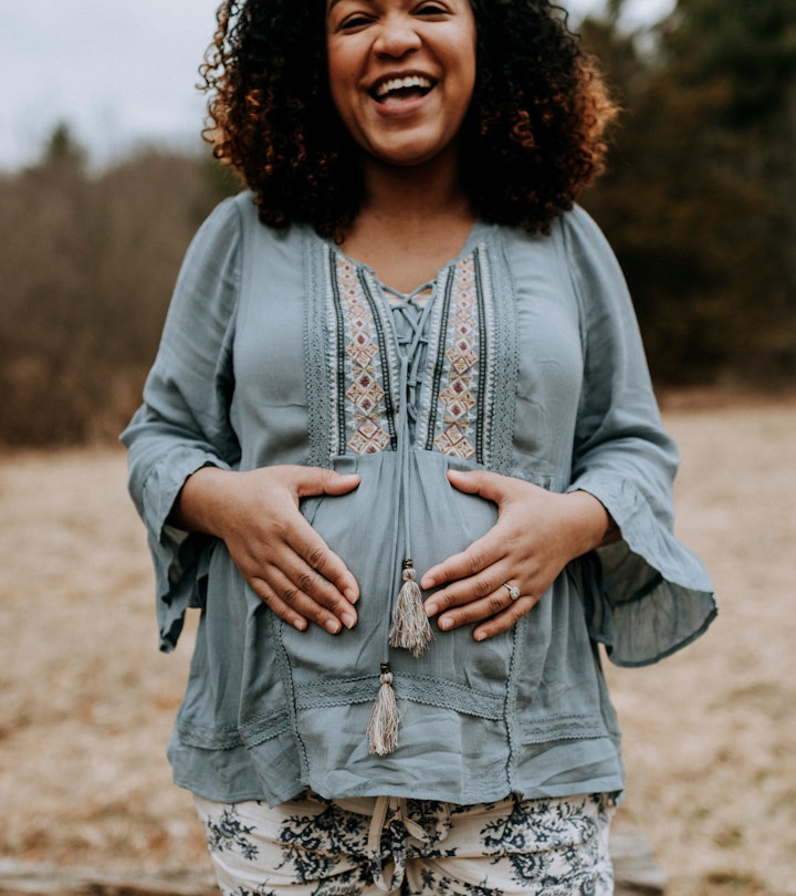 Happy pregnant woman smiling and holding her belly