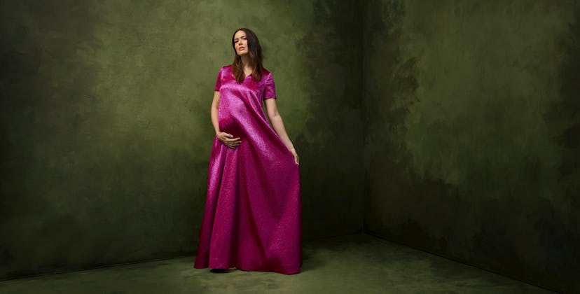 Mandy Moore wearing a long satin magenta dress while posing for her pregnancy photos