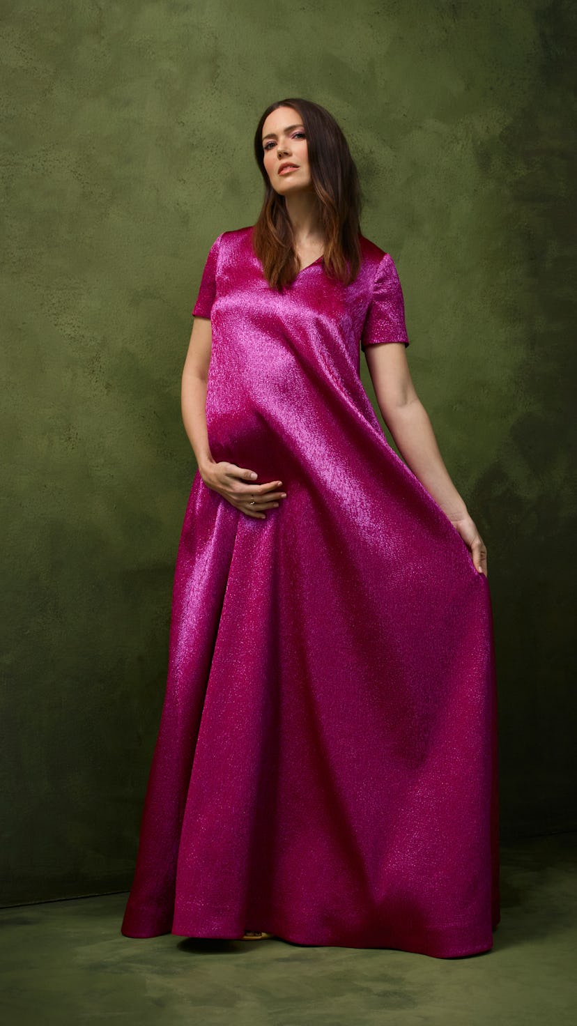 Mandy Moore wearing a long satin magenta dress while posing for her pregnancy photos