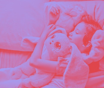 A child lays hugging a pink stuffed animal
