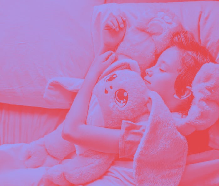 A child lays hugging a pink stuffed animal