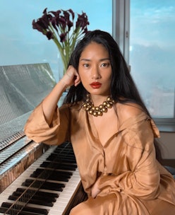 The pianist and composer Chloe Flower, posing in a brown satin dress accessorized with a necklace ma...