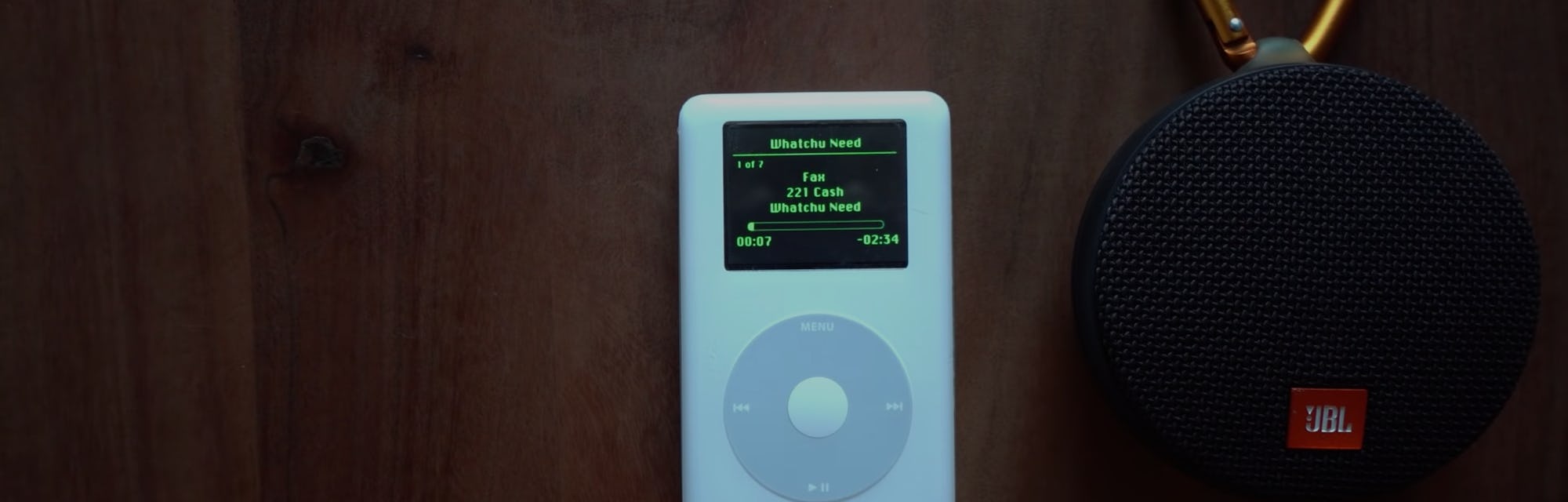 A screenshot of a 17-year-old iPod with Spotify streaming on it. It is placed next to a bluetooth sp...