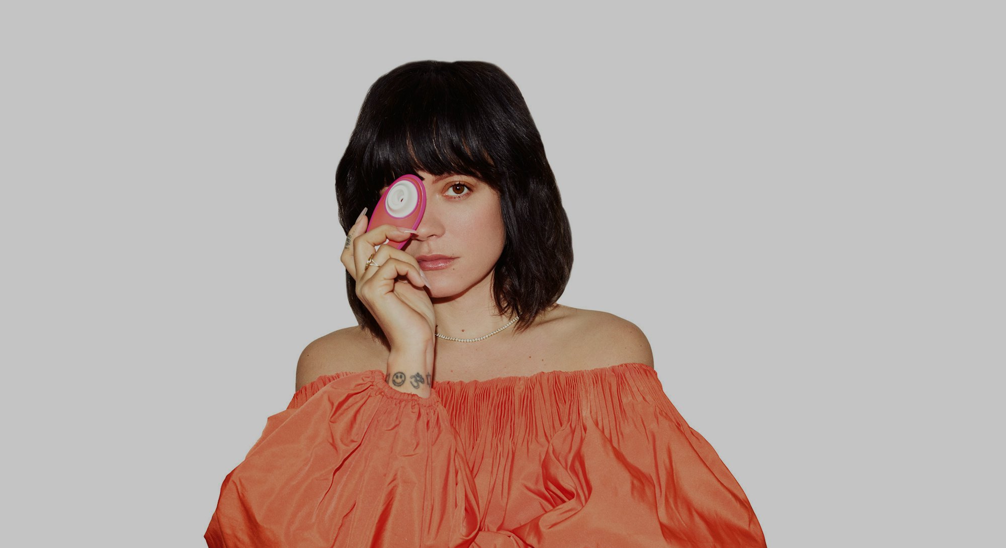 Singer Lily Allen poses with a Womanizer Liberty suction stimulator toy, holding it in front of her ...