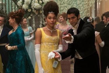 Marina from 'Bridgerton,' who is wearing a yellow gown, is led by hand to the dance floor by a smitt...