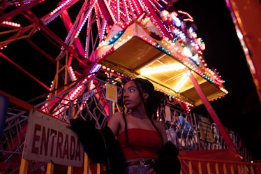 February 1 horoscope, young woman in front of ferris wheel, ride