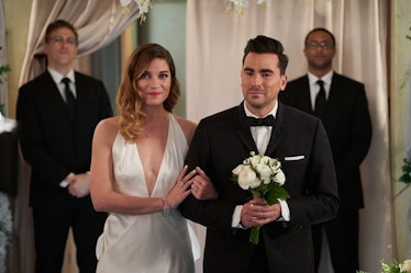 Alexis and David from 'Schitt's Creek' lock arms as they walk down the aisle at David's wedding.