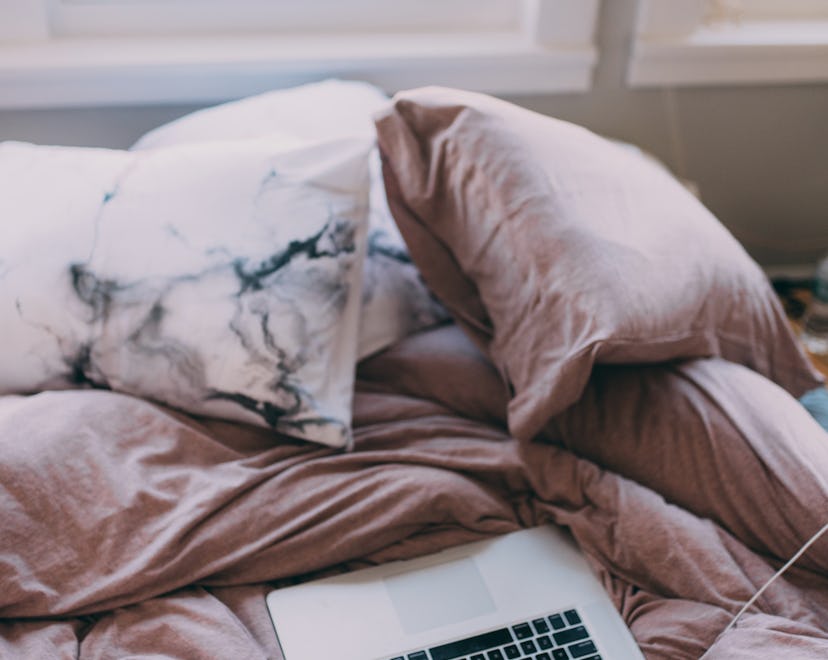open laptop on unmade bed