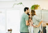 couple sweetly kissing in kitchen, holding infant between them, love captions for instagram