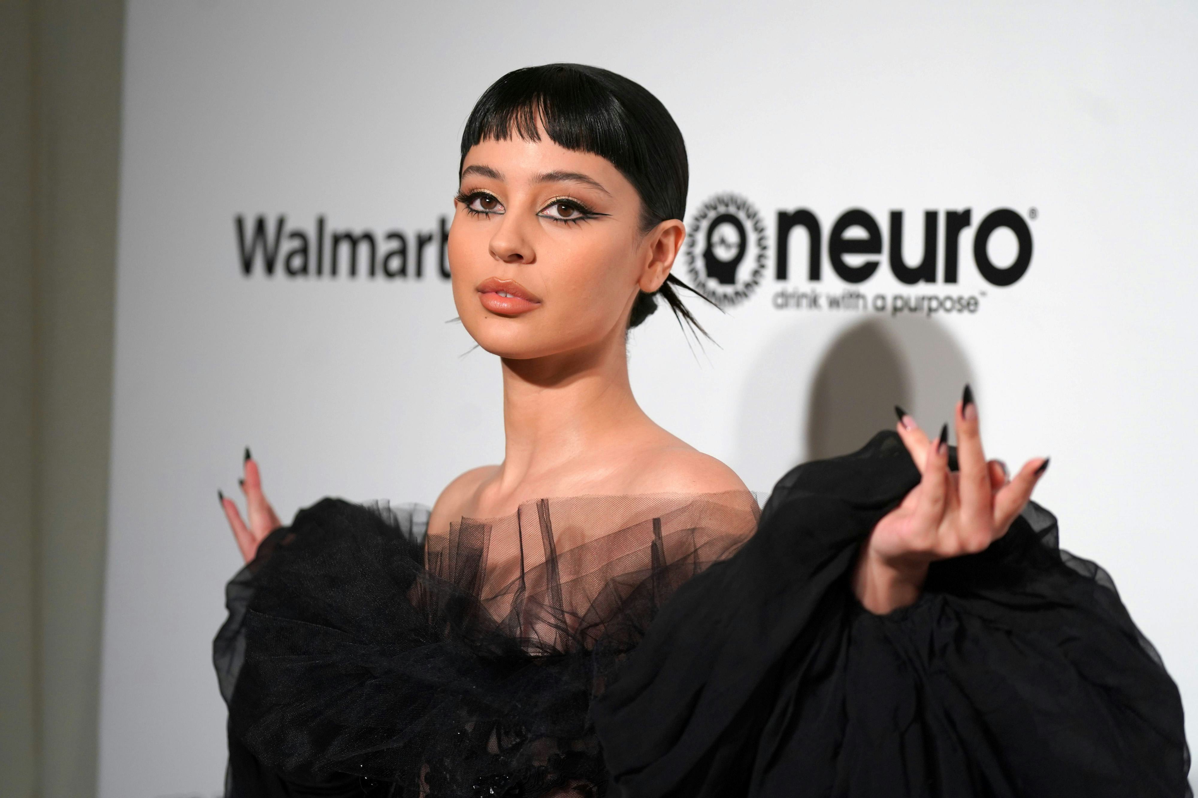 Alexa Demie, with short brunette bangs, poses on a red carpet