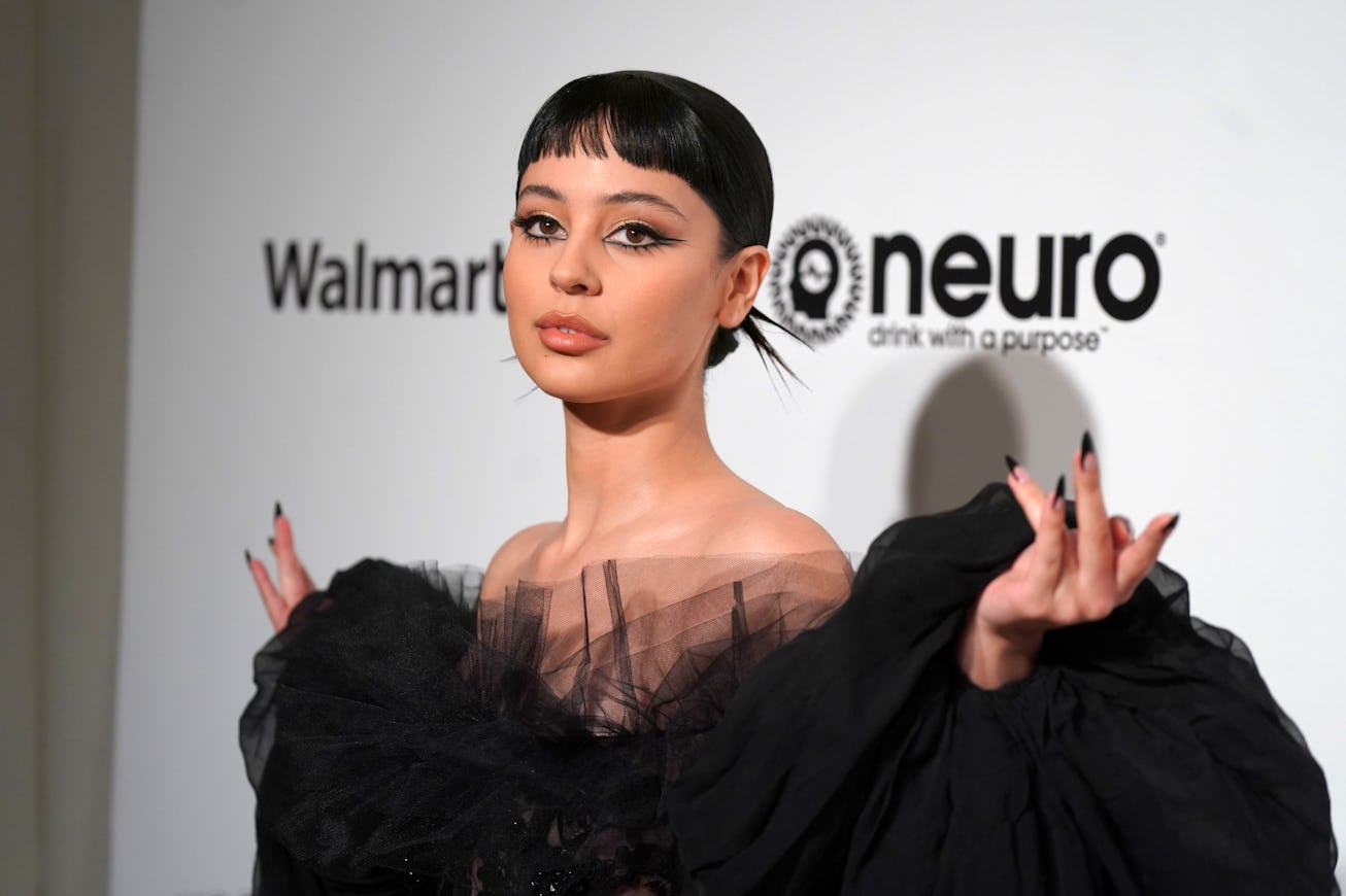 Alexa Demie, with short brunette bangs, poses on a red carpet