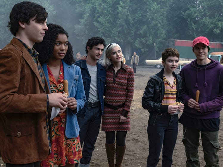 Sabrina and her friends from 'Chilling Adventures of Sabrina' stand around together in couple pairs ...