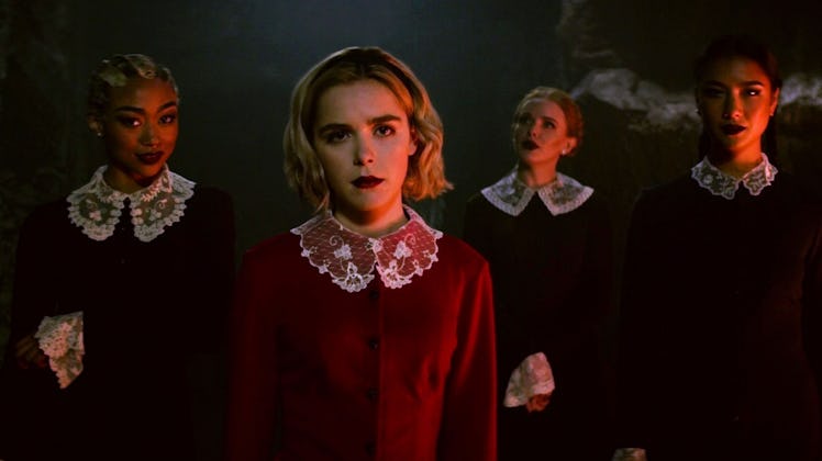 Sabrina and the Weird Sisters stand together in similar dresses in 'Chilling Adventures of Sabrina.'